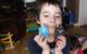 Five year old holds two of his wooden stacking robots and smiles.