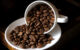 A cup of coffee beans pouring into a saucer that is also full of coffee beans. (Photo by Kishore Bhargava via Flickr/Creative Commons https://flic.kr/p/hDoQLX)