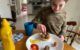 Nine year old smiles as he adds meatballs to his sandwich.