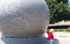 A youngster pushes the Grand Kugel, a giant grey stone ball. (Photo by rmanoske via Flickr/Creative Commons https://flic.kr/p/a8v85X)