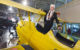 Wally Funk stands and smiles inside a yellow open cockpit airplane. (Photo by Pearl Harbor Aviation Museum via Flickr/Creative Commons https://flic.kr/p/24RSeTv)