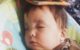 One year old is taking a nap in his bouncy chair with a book on his head.