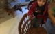 Four year old has his legs "trapped" between two wooden dining room chairs.