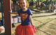 Two year old is happy because she's dressed up as Supergirl.