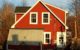 A red house with a grey solar-like room in front.