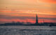 The Statue of Liberty at sunset, with a bright orange sky in the background. (Photo by ChrisGoldNY via Flickr/Creative Commons https://flic.kr/p/RHquTU)