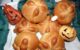 Six pan de muerto next to two small jack o'lantern decorations. (Photo by Eduardo Francisco Vazquez Murillo via Flickr/Creative Commons https://flic.kr/p/aBnpK7)