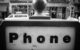 A black and white photo of the top of a phone booth, with a sign that reads "Phone." (Photo by Andrew Leonard via Flickr/Creative Commons https://flic.kr/p/D2cxtY)